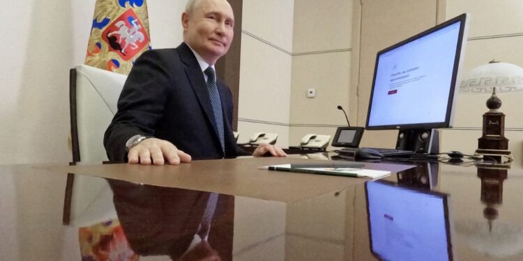 In this pool photograph distributed by Russia's state agency Sputnik, Russian President Vladimir Putin votes online in the presidential election at the Novo-Ogaryovo state residence, outside Moscow, on March 15, 2024. (Photo by Mikhail METZEL / POOL / AFP)